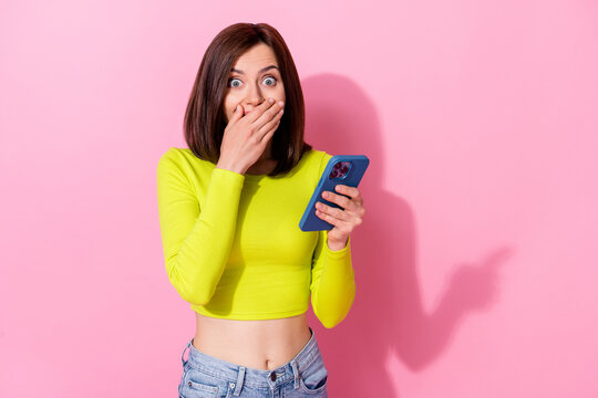 Photo of pretty shocked lady wear yellow top arm cover lips reading modern gadget empty space isolated pink color background