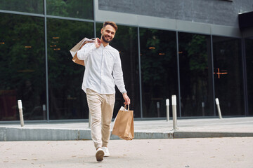 Shopping day. Stylish young man is outdoors with bags