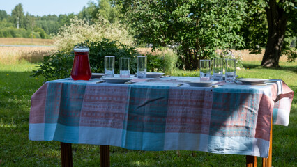 Prepare the country holiday lunch table. Juice cup with glasses. On a cotton tablecloth