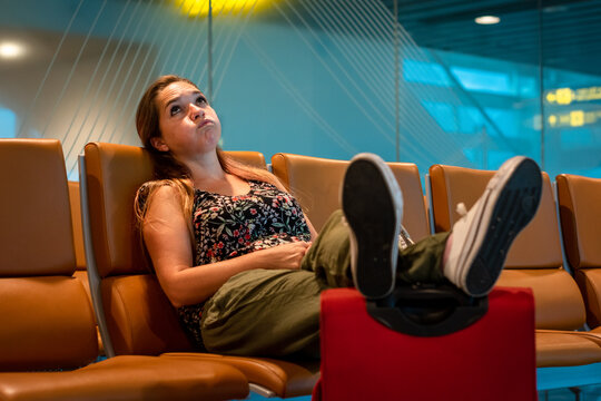 Mujer turista impaciente esperando en zona de embarque de aeropurto, porque su vuelo fue cancelado