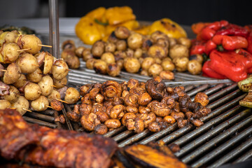 Ukrainian street food - potatoes, tomatoes, peppers and mushrooms baked on a round grill outdoors