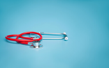 Doctor's red stethoscope on blue background, health insurance concept.