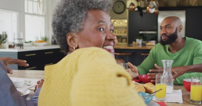 Video of happy african american grandmother turning and smiling at family breakfast table