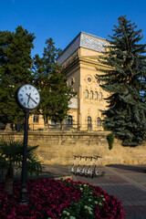 The historical Philharmonic Hall and the city street clock among the green foliage of trees on a clear summer sunny day