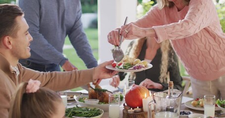Video of happy caucasian parents, daughter and grandparents serving food at outdoor table
