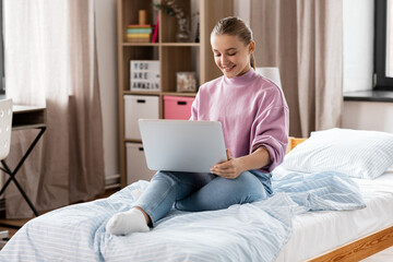 children, education and learning concept - happy smiling student girl with laptop computer at home