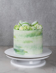 tall cake with green cream and decor of macarons
