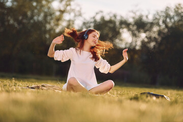 Obraz premium Young girls is enjoying the music. On the field at sunny daytime having nice weekend