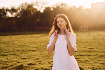 Young girl is on the field at sunny daytime having nice weekend