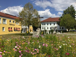 Prächtig blühende Wildblumen Wiese mit einem traditionellenWegkreuz vor  einem bayerischen...