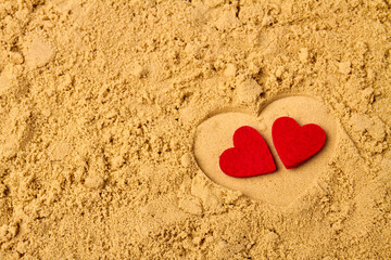Fototapeta premium Two red hearts on the beach sand. Honeymoon vacation concept.