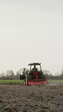 A young farmer drives a tractor across the field, plowing it with a plow