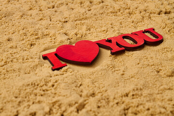 Fototapeta premium Close up red wooden I love you cutout on the sand. Honeymoon vacation concept.
