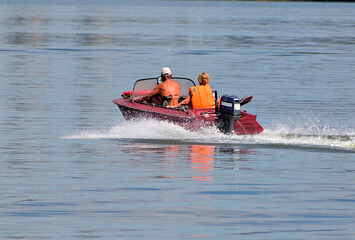 A man and a woman are sailing on a motor boat on a river on a summer day