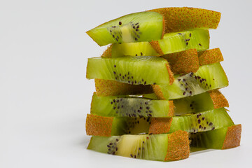 Macro photo of overlapping kiwi pieces. Tower of kiwi pieces. Jenga game created with pieces of kiwi. Citric fruits. Tropical fruits.