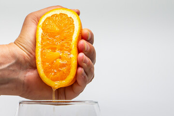 Macro photo of an orange squeezed with a hand. Orange juice. Side photo. Citrus fruit juice....