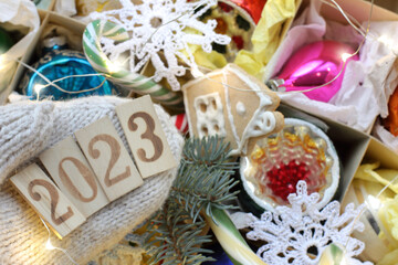 number 2023 on a knitted mitten against the background of Christmas tree decorations close-up. getting ready for new year and Christmas