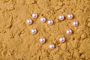 Close up pearls in the shape of heart. Wet sand and copy space.