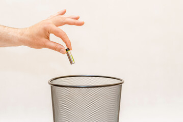 The Metal AA alkaline battery is thrown into the trash basket for disposal and recycling.White,gray background,selective focus,copy space.