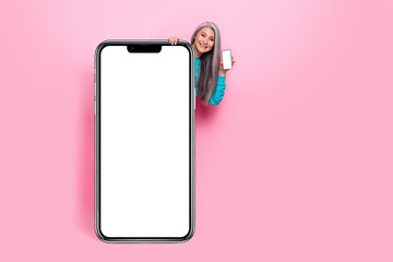 Photo of dreamy beautiful lady pensioner dressed blue pullover standing behind modern device empty space isolated pink color background