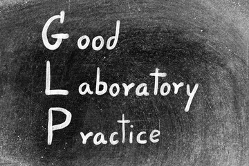 Fototapeta premium White chalk hand writing in word GLP Good laboratory practice on blackboard background