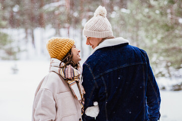people, love and leisure concept - happy smiling couple looking at each other in winter forest