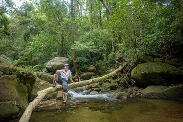 A female tourist sits on a log in the middle of a lush forest.