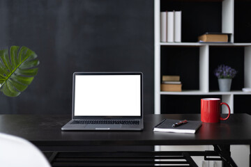 Laptop screen, Laptop Computer, notebook copy space, and eyeglasses sitting on a desk in a large open plan office space after working hours