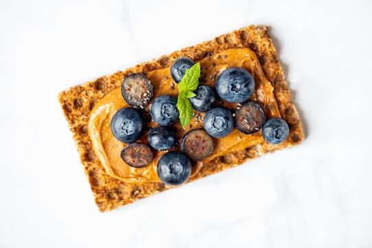 Open sandwich with blueberries. Made from wholegrain crispbreads and peanut butter, healthy nutritious snack option