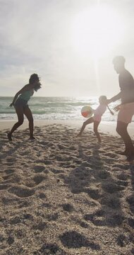 Vertical video of happy biracial family playing on sunny beach