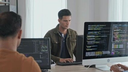 Waist up slowmo of team of Indian programmers working on computers, writing program codes for new software