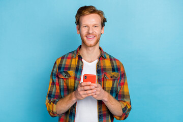 Photo of stylish handsome cheerful man with ginger hair dressed checkered shirt holding smartphone...