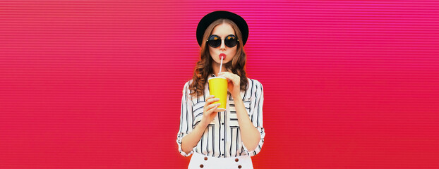 Portrait of stylish young woman drinking fresh juice wearing summer hat on pink background, blank copy space for advertising text