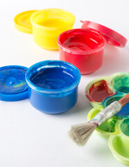 close-up of opened gouache color jars and acrylic paints, with a brush and palette, isolated on...