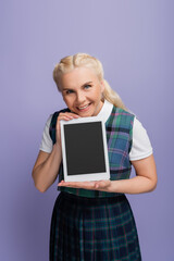 Smiling student holding digital tablet with blank screen isolated on purple