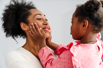 African american happy woman smiling and hugging her daughter at home