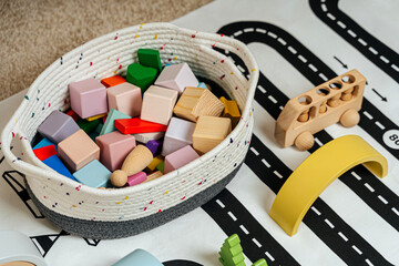 Cotton basket with wooden blocks for children's  games in playroom. Educational game for baby and toddler in modern nursery.
