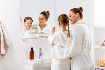 beauty, hygiene, morning and people concept - happy smiling mother and little daughter with dental...