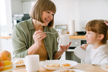 Obraz na płótnie Canvas White blonde girl having breakfast with her grandmother