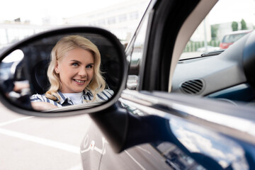 Positive woman reflecting in blurred car mirror