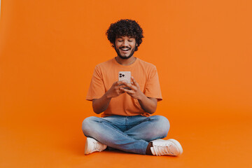 Young handsome indian smiling man sitting with phon