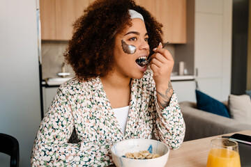 Young beautiful african woman with eye pathces eating breakfast