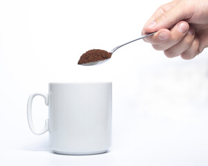 Hand holding a coffee spoon over a mug.