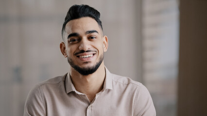 Portrait of confident calm young man arabic ethnic male handsome brunet guy turn head at camera happy male human bearded face positive smiling hispanic millennial businessman shows toothy health smile