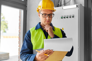 construction business and building concept - male electrician or worker in helmet and safety west...