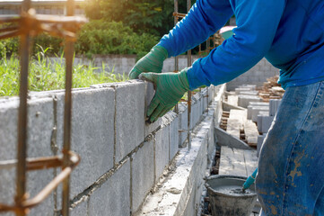masonry worker make concrete wall by cement block and plaster at construction site