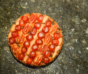 Top-down view of a round Genoa cake with cherries and nuts on a mottled background