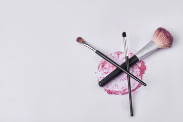 Top view pile of various makeup brushes. Round stain of cosmetic powder.