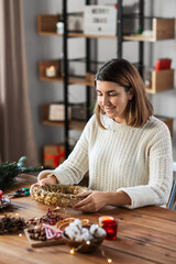 winter holidays, diy and hobby concept - happy smiling woman with hay basis making christmas wreath at home