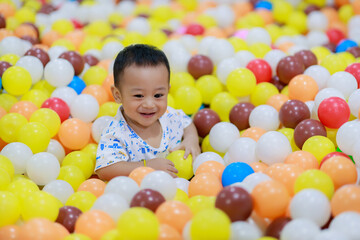 Fototapeta na wymiar Asian cute baby is laughing and playing with toys feeling happy and cheerful on Indoor playground, Baby family concept.